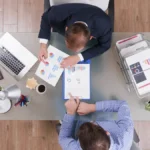 Mesa de reunião de indústria com planilha de custo por lead, ilustrando geração de leads em Joinville