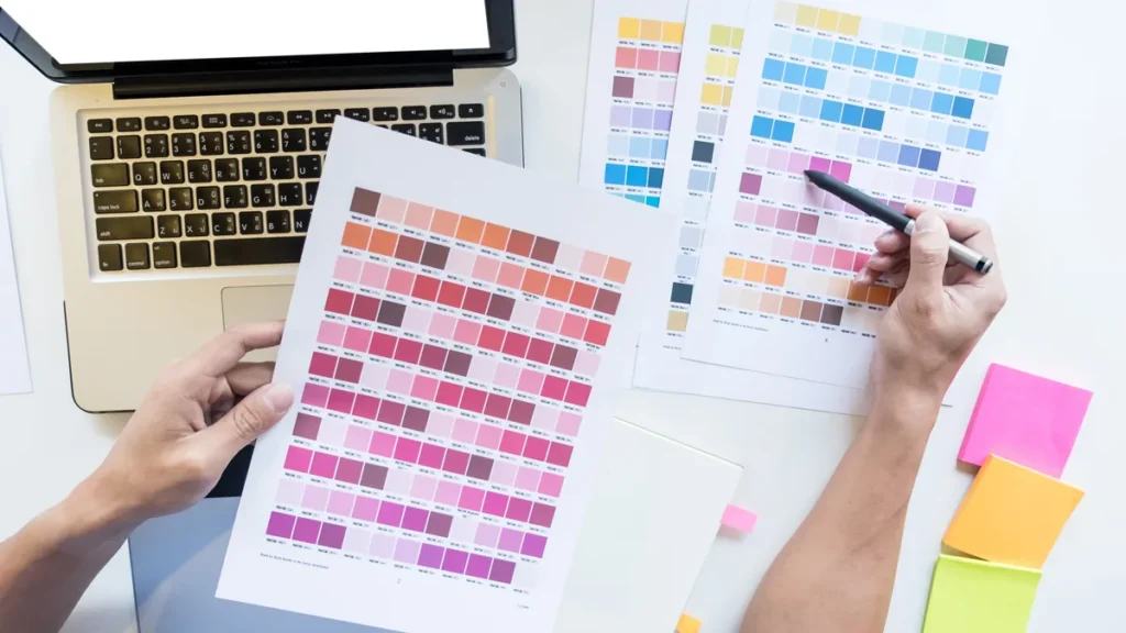 Mesa de designer com paleta de cores e páginas de manual de identidade visual para pequenas empresas