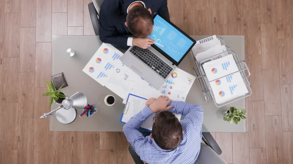 Mesa de escritório com planilha e laptop usados para avaliar o custo de anúncios no LinkedIn