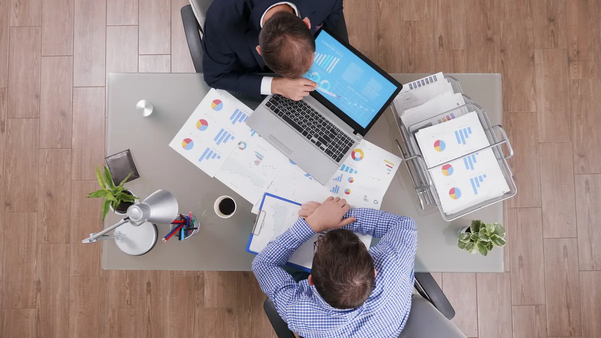 Mesa de escritório com planilha e laptop usados para avaliar o custo de anúncios no LinkedIn
